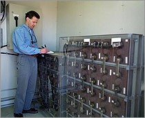 A photo of a researcher recording data from a translucent case containing batteries.
