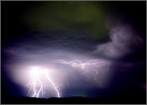 A photo of lightning striking, illuminating the dark, night sky.